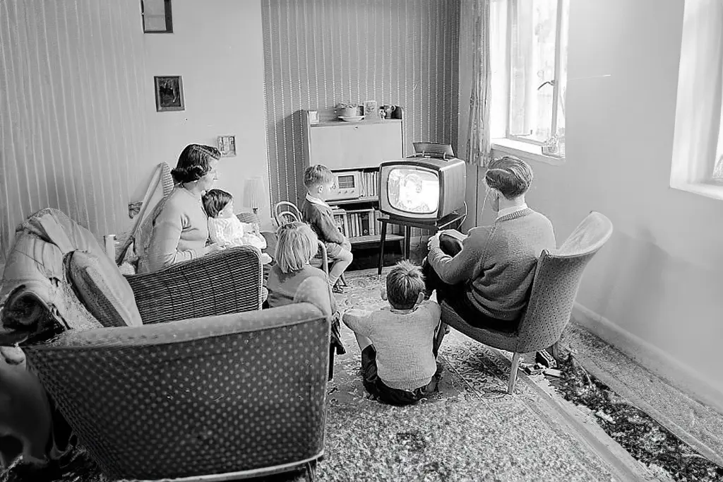 Família reunida na sala assistindo tv preto e branco.