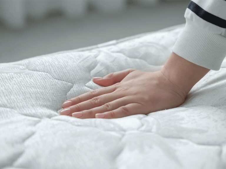 Mão testando conforto de colchão macio