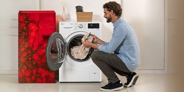 Homem utilizando máquina de lavar roupas moderna